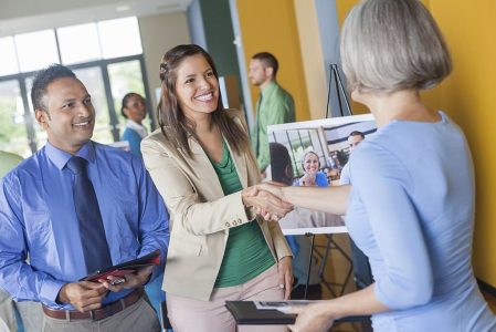 Woman shaking hands with professional executive at job fair event